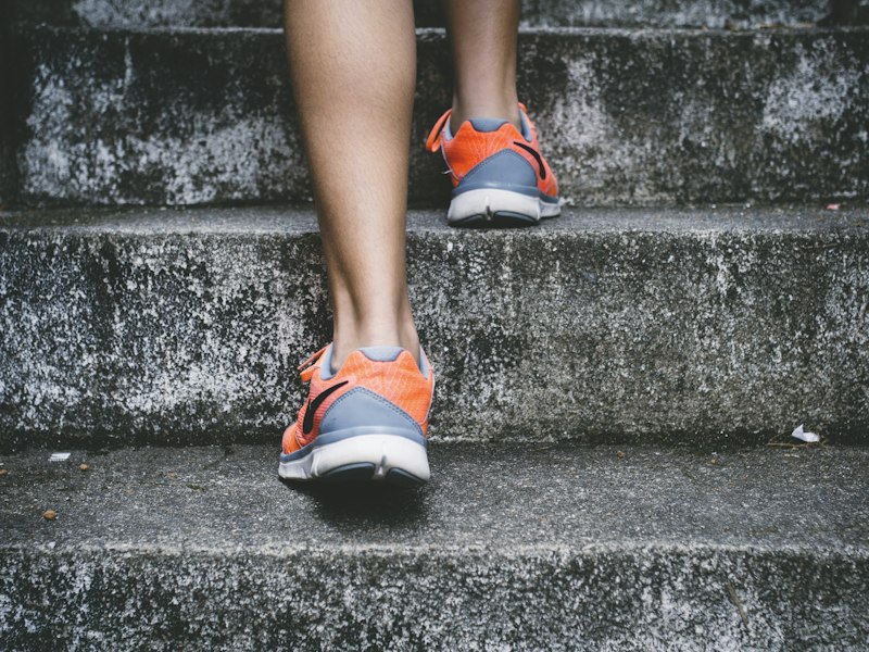 Piernas con zapatillas naranjas subiendo escaleras de concreto