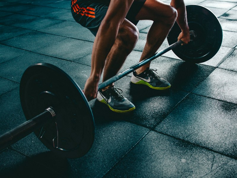 Persona preparándose para levantar una barra con discos en el gimnasio